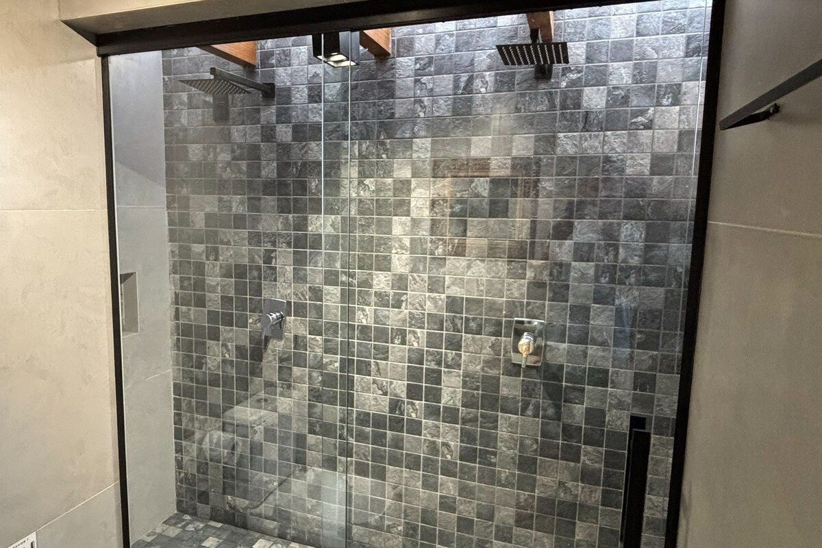 A shower with a glass door and a tiled wall.