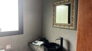 A bathroom with a marble sink, a black faucet, a mirror with an ornate frame, and a window providing natural light.