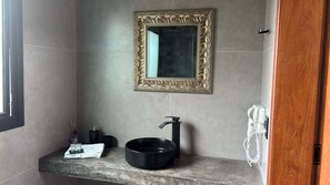 A bathroom with a large mirror, a black sink, and a hairdryer.