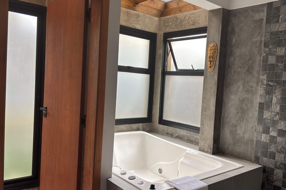 A bathroom with a bathtub, a shower, and a window with frosted glass.