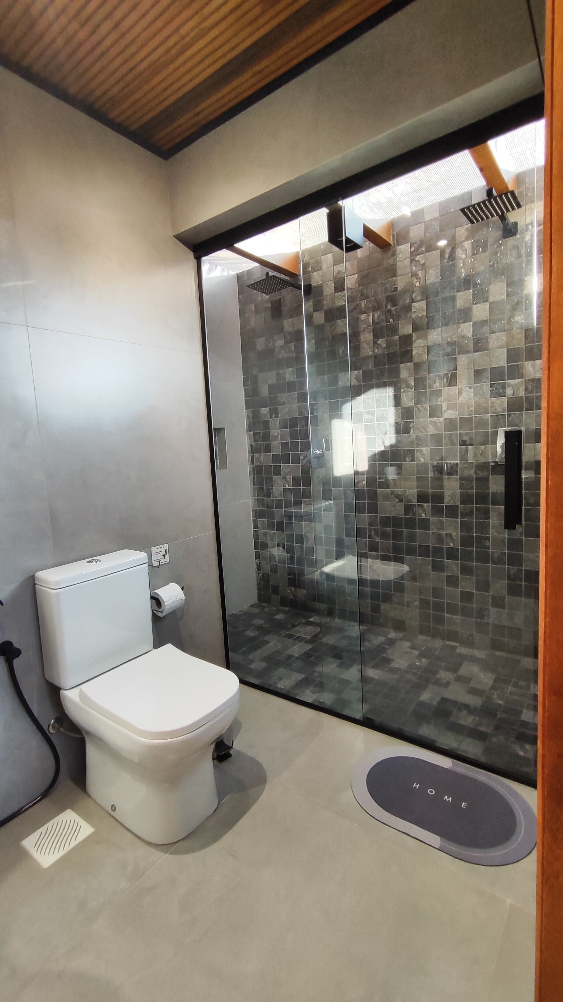 Un baño moderno con inodoro, cabina de ducha y puerta de cristal.