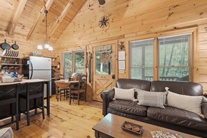 Ein gemütliches Blockhaus-Interieur mit Essbereich, Küche und Wohnzimmer mit Ledersofa.