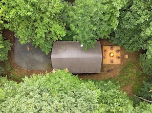 A rectangular building with a flat roof, surrounded by dense green foliage. - Little Rock Creek Cabin 1BDR (Cherry Log)