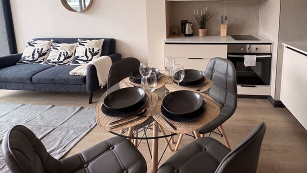 A modern living space with a sofa, dining table, chairs, and a kitchen area. - Santiago Centro Histórico-Domus Travels (Santiago)