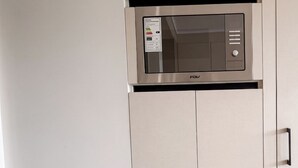 A kitchenette with a microwave, cabinets, and a small sink. - Santiago Centro Histórico-Domus Travels (Santiago)