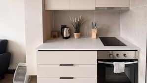 A compact kitchen with a built-in oven, a coffee maker, and a clock on the wall. - Santiago Centro Histórico-Domus Travels (Santiago)