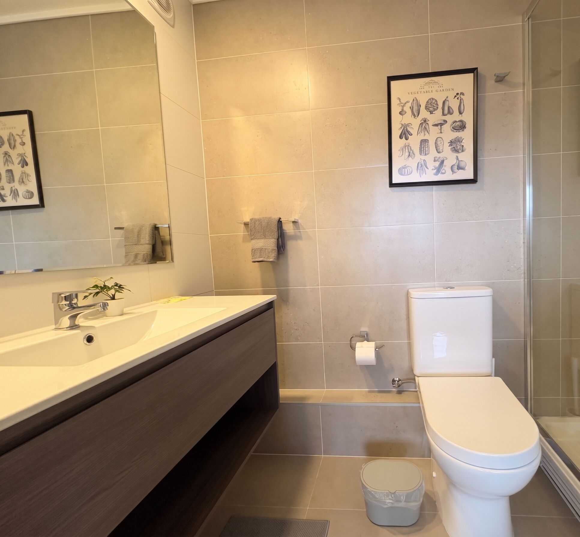 Ein modernes Badezimmer mit einem großen Spiegel, einem Waschbecken, einer Toilette und einer Duschkabine.