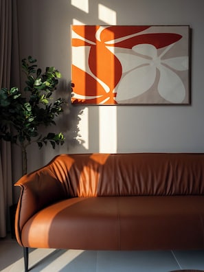 A brown leather sofa against a wall with a framed abstract painting.