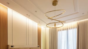 Een moderne hotelkamer met een groot bed, een houten hoofdbord, een inbouwledingkast en een ronde plafondlamp.