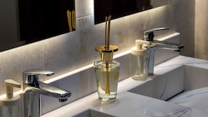 Een moderne badkamer met een grote spiegel, twee wastafels en een fles handzeep.