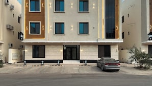 Een modern gebouw met een platte gevel, meerdere ramen en een auto ervoor geparkeerd.