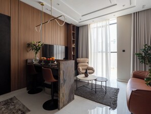 Uma sala de estar moderna com televisão, assentos, uma mesa de centro e uma planta.