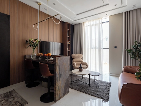 A modern living room with a TV, seating, a coffee table, and a plant.