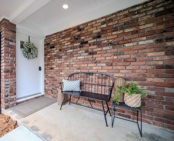 Un muro de ladrillo con un banco y una cesta de mimbre con plantas.