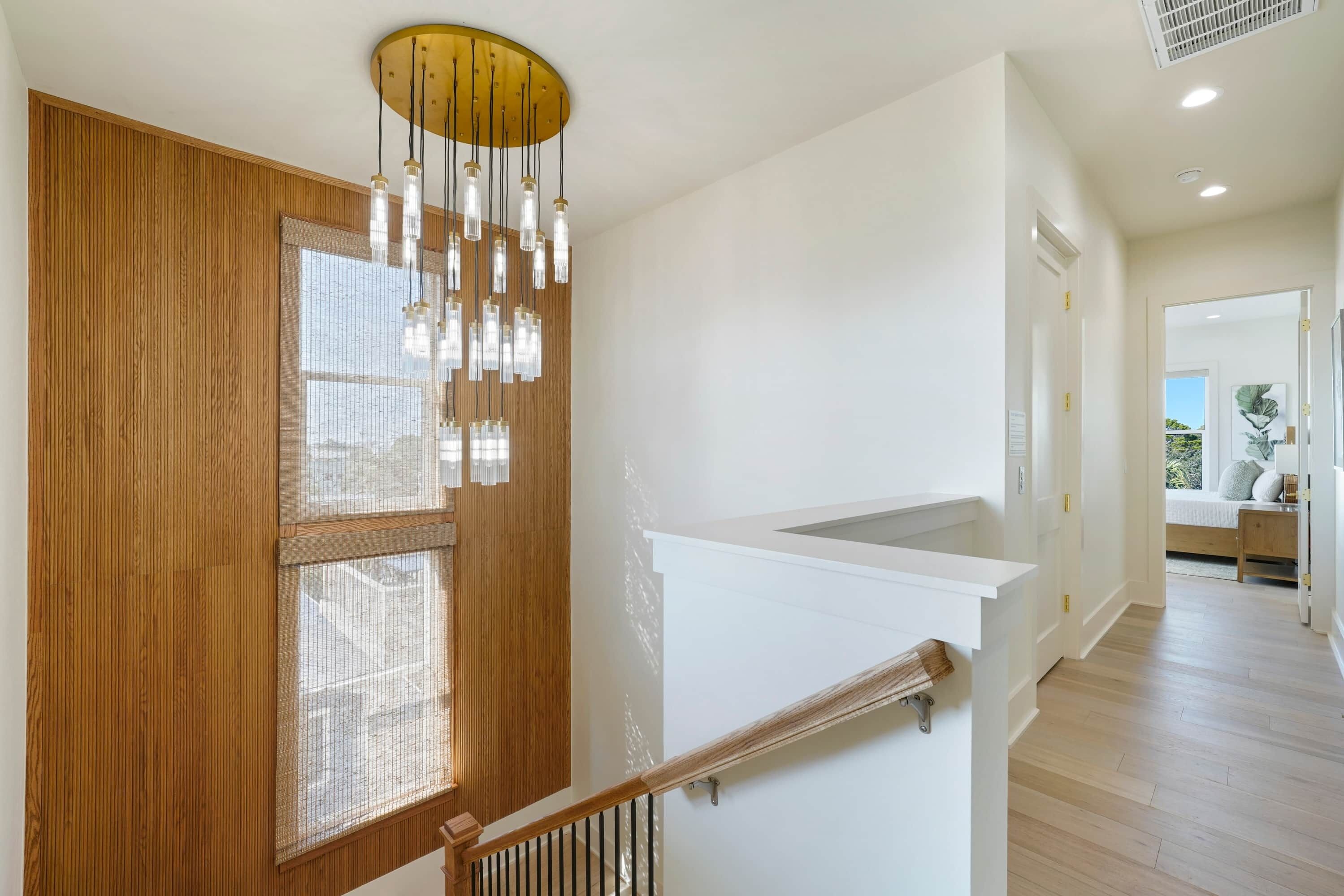 Ein modernes Interieur mit einer Holztreppe, einer weißen Wand und einer Deckenleuchte.