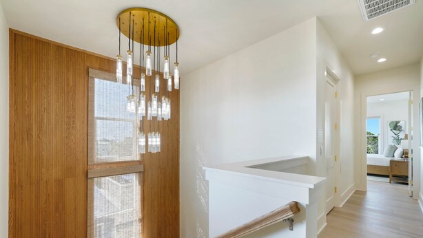 Un intérieur moderne avec un escalier en bois, un mur blanc et un luminaire au plafond.