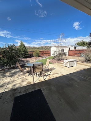 A patio with a table and chairs, a covered seating area, and a view of a hilly landscape. - Great 3 bedroom home for outdoor enthusiasts and families! (Mancos)