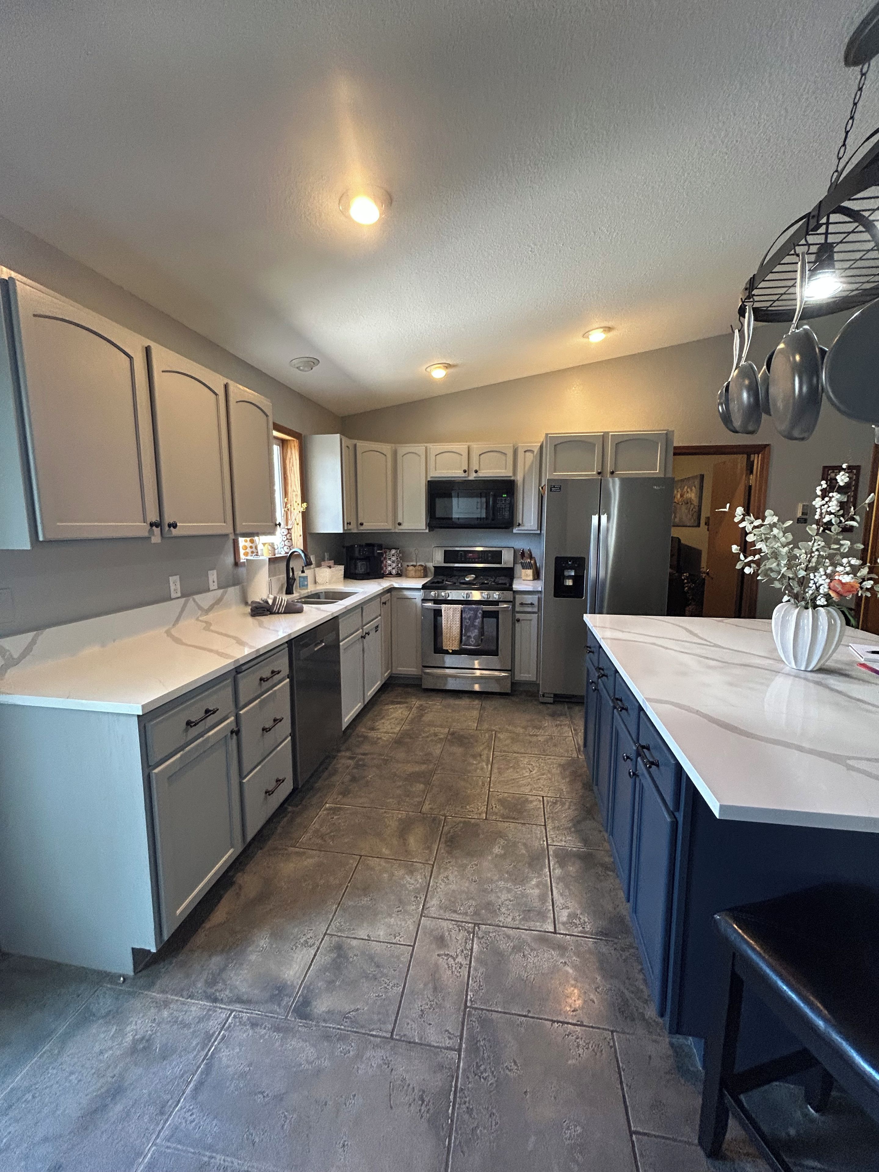 A kitchen with white cabinets, stainless steel appliances, and a tiled floor.