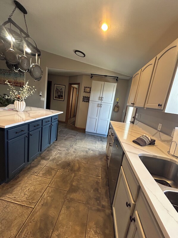 A kitchen with a central island, white cabinets, and a stainless steel sink. - Great 3 bedroom home for outdoor enthusiasts and families! (Mancos)