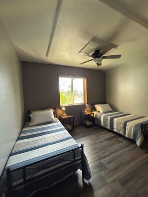 A room with two single beds, a ceiling fan, a window, and a small table with a lamp. - Great 3 bedroom home for outdoor enthusiasts and families! (Mancos)