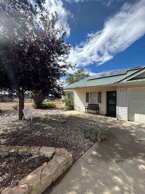 A building with a green roof, a bench, and a tree in the foreground. - Great 3 bedroom home for outdoor enthusiasts and families! (Mancos)