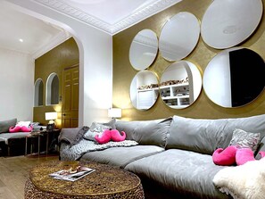 Een moderne woonkamer met een bank, een salontafel en een muur met meerdere spiegels.