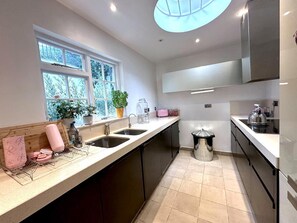 Een moderne keuken met een raam, een spoelbak, een fornuis en een vuilnisbak.
