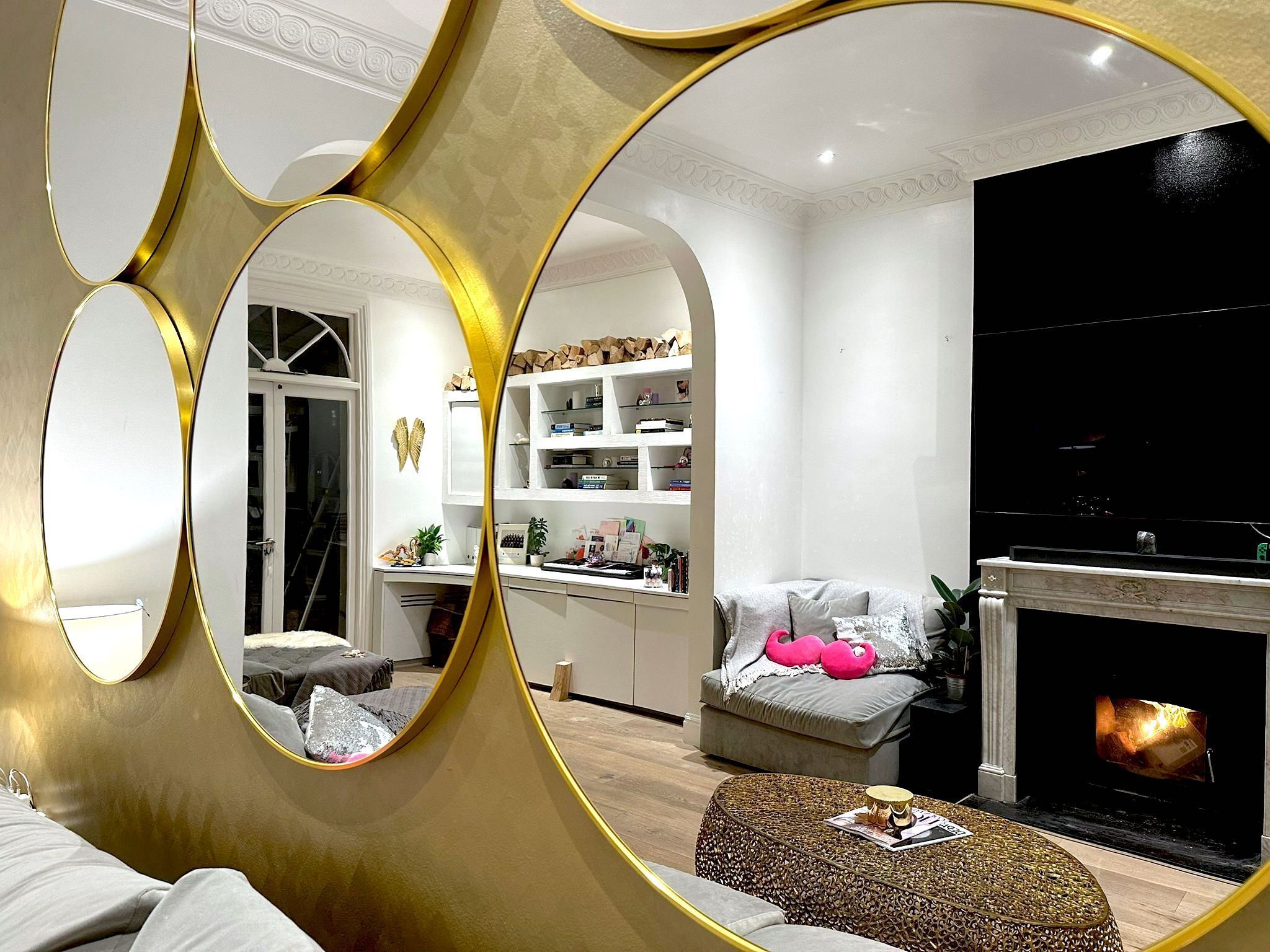 A modern living room with a fireplace, a sofa, a coffee table, and a mirrored wall.