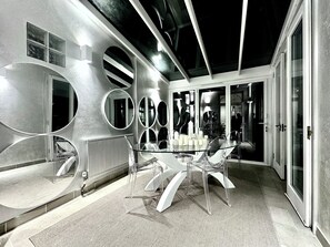 A modern interior with a glass table surrounded by clear chairs, a radiator, and multiple wall-mounted mirrors. - Maison de Paix - Knightsbridge.  Pure luxury in between Harrods  and Chanel. (London)