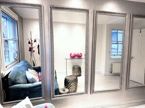 A room with a large mirror, a blue sofa, and a small round table with decorative items. - Maison de Paix - Knightsbridge.  Pure luxury in between Harrods  and Chanel. (London)
