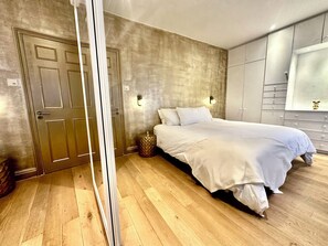Een slaapkamer met een bed, een kledingkast en een nachtkastje.