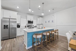 A modern kitchen with white cabinets, stainless steel appliances, and a blue accent wall.
