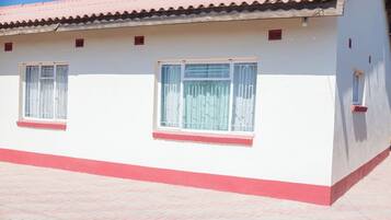 A building with two windows, a red roof, and a red base.