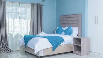 A bedroom with a bed, curtains, a nightstand, and a wardrobe.