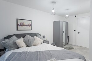 A modern bedroom with a bed, a wardrobe, a nightstand, and a framed cityscape picture on the wall. - One bed flat 7 mins walk to Manchester Piccadilly (Greater Manchester)