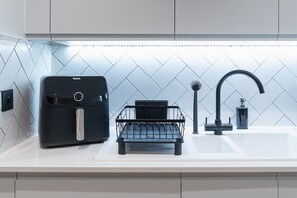 A kitchen with a modern air fryer, a black wire basket, and a faucet. - One bed flat 7 mins walk to Manchester Piccadilly (Greater Manchester)