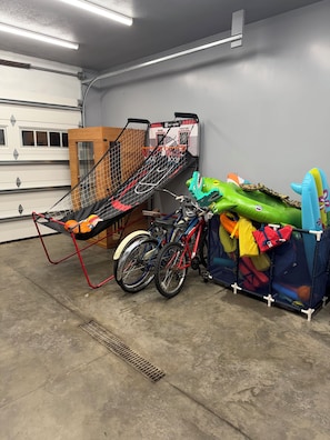 Eine Garage mit zwei Fahrrädern, einem Basketballkorb und einem aufblasbaren Hai in Grün.