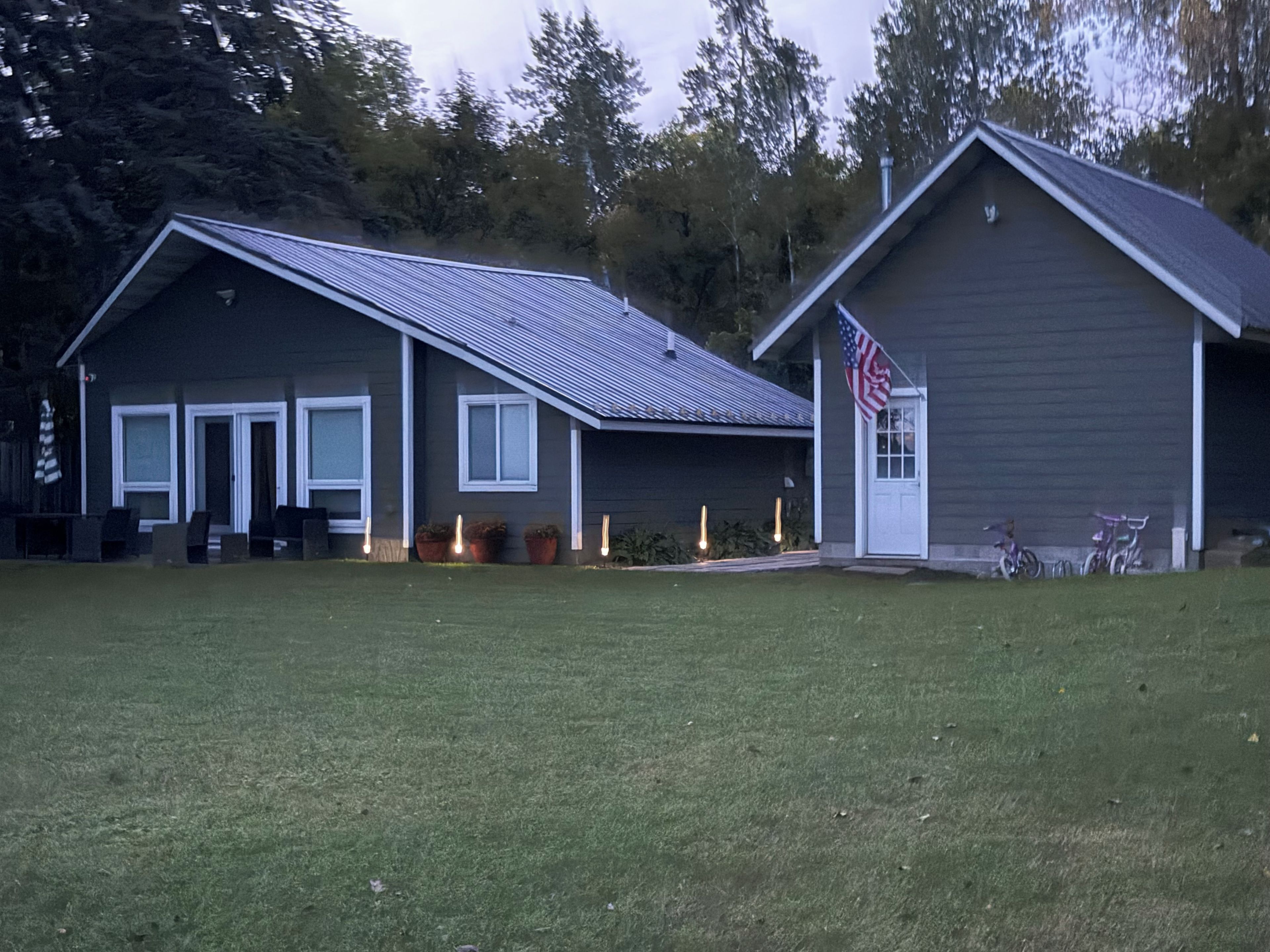 A two-story house with a front porch, a garage, and an American flag.