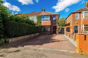 A two-story brick house with a paved driveway and a gated entrance. - 3 bed house · Driveway · EV Charger · Sleeps 7 (Greater Manchester)