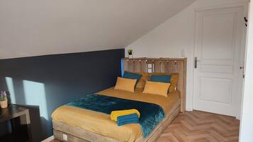 Een eenpersoonsbed met houten hoofdeinde, een nachtkastje en een potplant.
