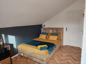 Una cama individual con cabecera de madera, una mesita de noche y una planta en maceta.