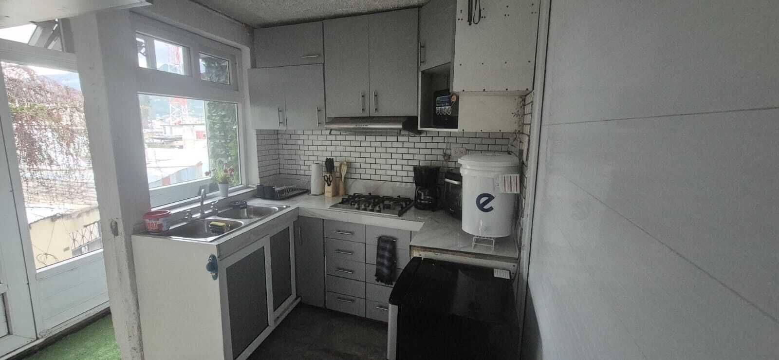 Cocina compacta con gabinetes blancos, estufa a gas y un lavamanos.