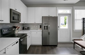 A modern kitchen with white cabinets, stainless steel appliances, and a built-in microwave. - Posh Park Circle Pad close to Charleston’s Best (North Charleston)