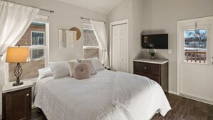 A bedroom with a bed, a nightstand, a TV, and a door.
