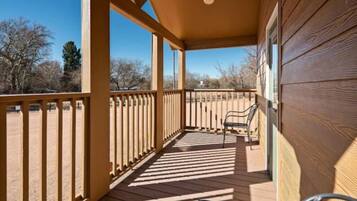 A wooden deck with a railing, a bench, and a bicycle.
