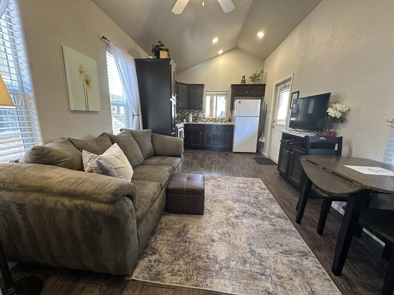 A compact living space with a sofa, ottoman, dining table, and kitchen area.