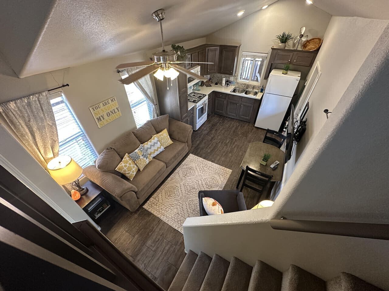 A modern apartment with a living room, kitchen, and staircase.