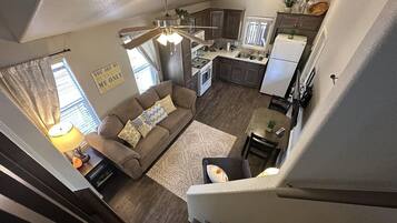 A modern apartment with a living room, kitchen, and staircase.