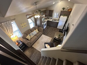 Un apartamento moderno con sala de estar, cocina y escalera.