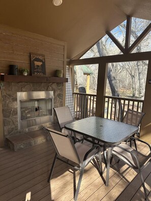Un patio al aire libre con chimenea de piedra, mesa y sillas de metal.